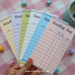 Colorful reading log bookmarks displayed on an open book, with spaces to track titles, reading dates, and star ratings by Elaine Girls